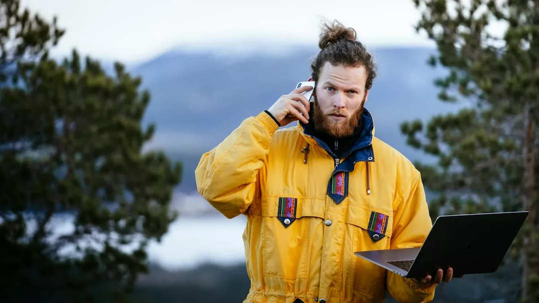 a man in a yellow jacket holding a laptop